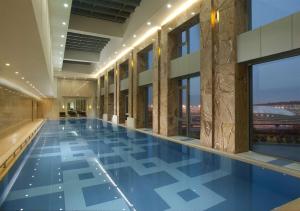 ein großer Pool in einem Gebäude mit blauen Fliesen in der Unterkunft Hilton Beijing Capital Airport in Shunyi