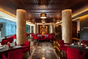 un ristorante con sedie rosse e tavoli in una stanza di Hilton Beijing Capital Airport a Shunyi