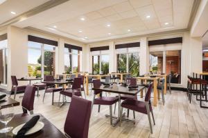 a restaurant with tables and chairs and windows at Hilton Garden Inn Atlanta South-McDonough in McDonough