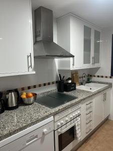 uma cozinha com armários brancos e um forno com placa de fogão em MARGO EL EDEN Residencial em Gandia