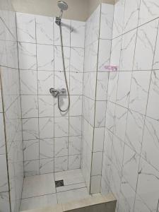 ein Bad mit einer Dusche und weißen Marmorfliesen in der Unterkunft Біля Замку in Lwiw