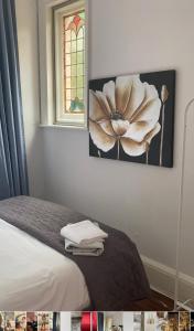 ein Schlafzimmer mit einem Bett mit einem Blumengemälde an der Wand in der Unterkunft Cleddon in Bournemouth