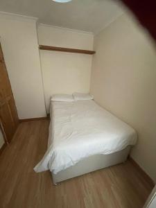 a small bedroom with a bed with white sheets at NKY CRYSTAL 4 Bed House Apartment in London
