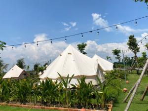 une grande tente blanche avec une chaîne de lumières dans l'établissement Sky Camping, à Củ Chi