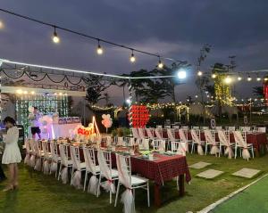 un groupe de tables avec des chaises et des lumières blanches dans l'établissement Sky Camping, à Củ Chi