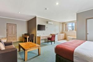 a hotel room with a bed and a desk and a kitchen at Quality Inn Colonial in Bendigo