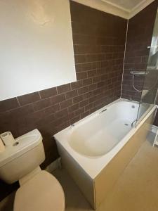 La salle de bains est pourvue de toilettes et d'une baignoire. dans l'établissement NKY CRYSTAL 4 Bed House Apartment, à Londres