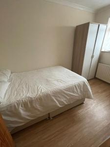 um quarto com uma cama branca e uma janela em NKY CRYSTAL 4 Bed House Apartment em Londres