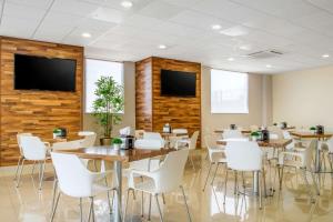 a restaurant with tables and white chairs and a flat screen tv at Sleep Inn Hermosillo in Hermosillo