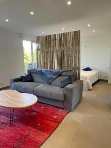 ein Wohnzimmer mit einem Sofa, einem Tisch und einem Bett in der Unterkunft Le Cèdre Magnifique Appartement à Cannes in Cannes
