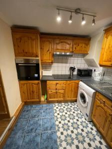 a kitchen with wooden cabinets and a washing machine at NKY CRYSTAL 4 Bed House Apartment in London