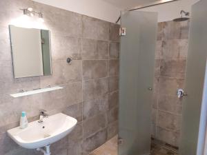 a bathroom with a sink and a mirror and a shower at Szárszó Apartmanok in Balatonszárszó +19 photos