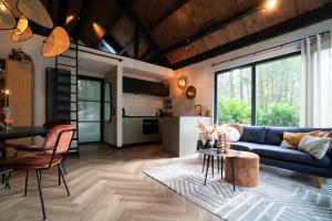 a living room with a blue couch and a table at Fantastisch luxe boshuis I Onthaasten in de natuur in Emst