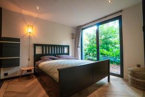 1 dormitorio con cama y ventana grande en Fantastisch luxe boshuis I Onthaasten in de natuur en Emst