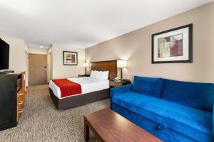 a hotel room with a bed and a blue couch at SureStay Plus by Best Western Reading North in Reading +20 photos