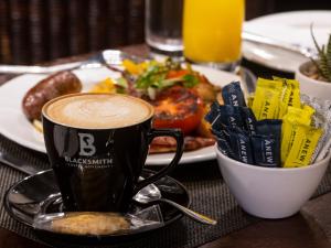 a cup of coffee on a table with a plate of food at Hilton Homestead by ANEW in Pietermaritzburg