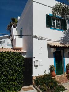 Biały dom z zielonymi drzwiami i płotem w obiekcie Casa Rustica w mieście Olhão