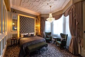 a bedroom with a bed and two chairs and a chandelier at 100 Queen’s Gate Hotel London, Curio Collection by Hilton in London