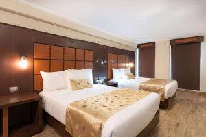 Habitación de hotel con 2 camas y escritorio en Sleep Inn Puebla Centro Hist rico en Puebla