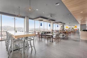 a restaurant with tables and chairs and large windows at Arte Hotel Bandar Lampung in Bandar Lampung