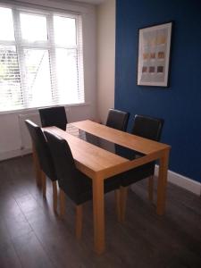 a dining room with a wooden table and chairs at Whitworth House, Sleeps 6 TVs in all bedrooms, WIFI - 3 bedroom in Northampton