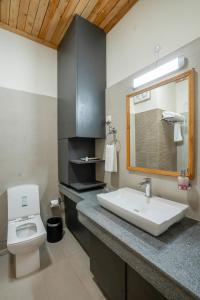 a bathroom with a sink and a toilet and a mirror at Ezzenza Swarg by Beas Golf Resort - Devlok Manali in Baragrān