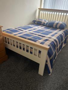 a bedroom with a bed with a blue and white comforter at Self contained room, en-suite with separate lockable front door, located in an exclusive area in Wednesbury