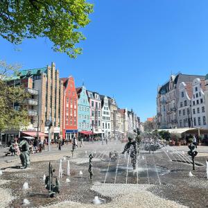 un grupo de personas de pie alrededor de una fuente en una ciudad en Roam Sweet Roam - private Zimmervermietung, en Rostock