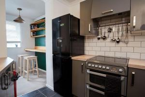 een keuken met een fornuis en een zwarte koelkast bij Premium Central Stroud Apartment with Parking x2 