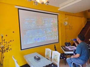 a man sitting at a table in front of a projection screen at YuanWai in Wujie