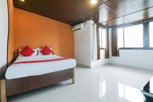 a bedroom with a bed with orange walls and a window at Flagship Dewa Near Dabolim Airport in Vasco Da Gama