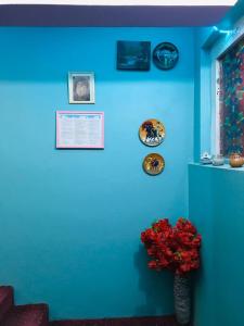 un muro blu con un vaso di fiori rossi sopra. di Millat Hotel & Noor Jahan Hotel Kandahar a Kandahar