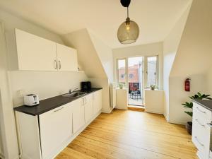 cocina con armarios blancos y suelo de madera en aday - 1 bedroom balcony apartment on the pedestrian street in Randers en Randers