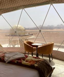 a bed and chairs in a room with a large window at RUM EiLEEN LUXURY CAMP in Wadi Rum