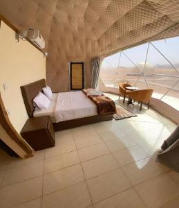 a bedroom with a bed and a desk and a window at RUM EiLEEN LUXURY CAMP in Wadi Rum
