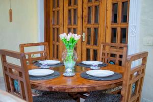 uma mesa de madeira com pratos e um vaso de flores em Tembo Court Beach Cottage em Malindi