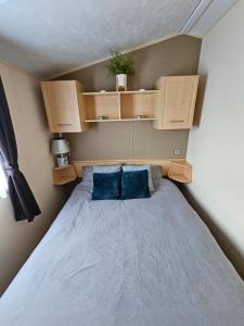 a small bedroom with a bed with blue pillows at NEW Orla Caravan in Meliden