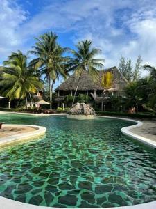 einen Pool mit Palmen und ein Haus in der Unterkunft Tembo Court Beach Cottage in Malindi