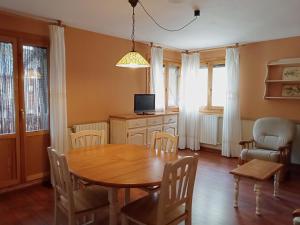 comedor con mesa, sillas y TV en Apartamentos Gavín Biescas 3000, en Gavín