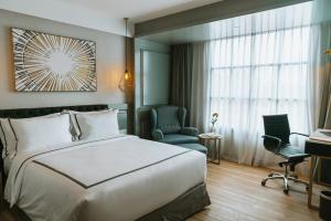 una camera d'albergo con un letto, una sedia e una finestra di Barito Mansion a Giacarta