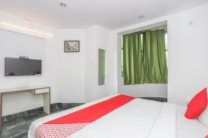 sypialnia z czerwono-białym łóżkiem i telewizorem w obiekcie Hotel Townhall w mieście Bengaluru