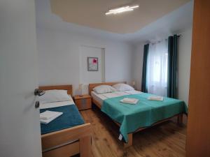 - 2 lits dans une petite chambre avec des draps verts dans l'établissement Apartments Fida, à Vir