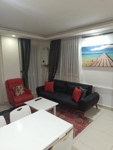 a living room with a black couch and a red chair at AQUA CİTY SUİT in Antalya