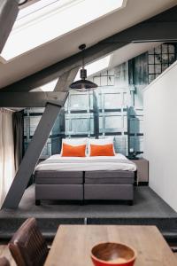 YAYS Amsterdam Maritime by Numa في أمستردام: غرفة نوم مع سرير مع وسائد برتقالية وطاولة