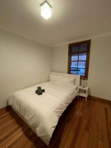 a bedroom with a white bed with a hat on it at Comfortable 3 Bedroom House Pyrmont in Sydney
