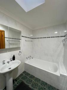 a white bathroom with a sink and a bath tub at Comfortable 3 Bedroom House Pyrmont in Sydney
