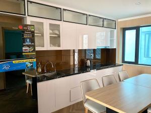 a kitchen with white cabinets and a table with chairs at Milash Boutique Hotel in Ha Long