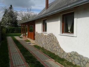a white house with a stone wall and a window at Munkácsy Apartmanok in Balatonfenyves