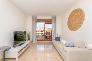 sala de estar con sofá blanco y TV en 238 Ático Playa del Angel, en Estepona
