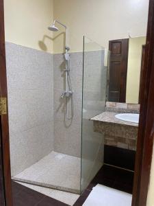 ein Bad mit einer Dusche und einem Waschbecken in der Unterkunft Tranquility three bedroom house with Wi-Fi in Daressalam